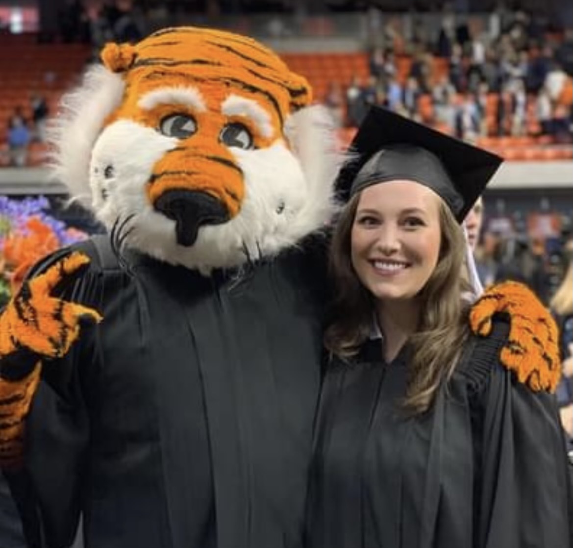 Auburn University graduate posing with Auburn mascot at graduation ceremony in Auburn Alabama