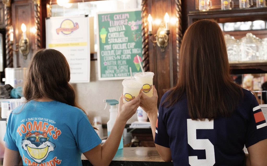 Two people holding lemonade inside Toomer’s Drugs in Auburn, Alabama, capturing everyday local life in the Auburn and Opelika area.