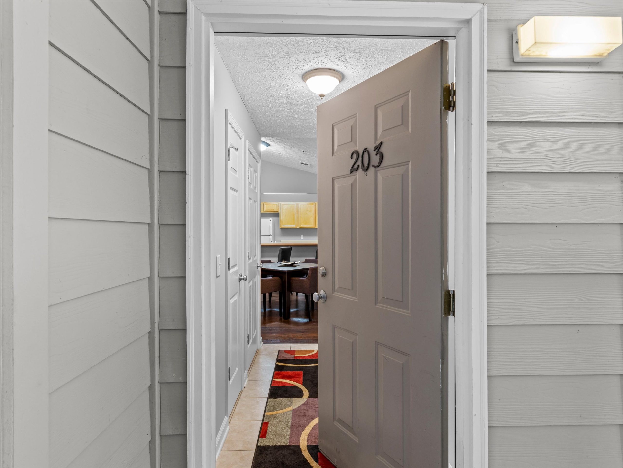 Entry view of Southern Edge condo Unit 3-203 in Auburn, Alabama, showing private front door and interior hallway leading into open living space
