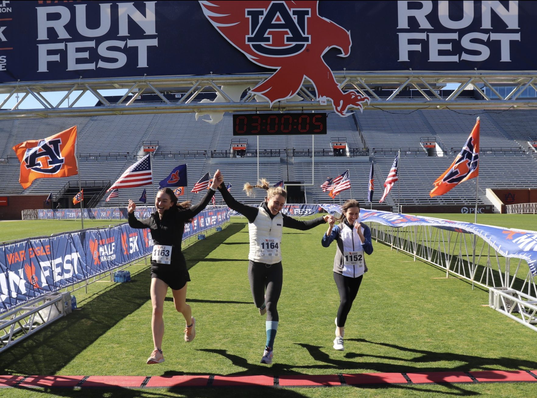 Runners crossing the finish line at War Eagle Run Fest inside Jordan-Hare Stadium in Auburn, Alabama